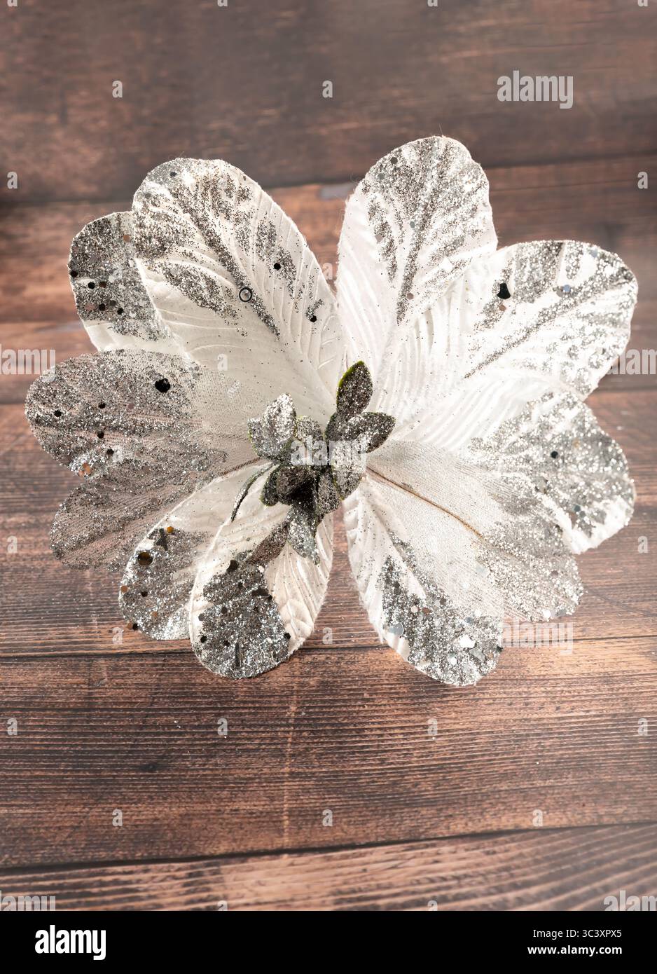 Glitzernde handgemachte silberne Weihnachtsstern auf rustikalem Holzhintergrund. Ideal für Weihnachtsbasteln, Weihnachtsdekor und kreative Winterprojekte. Stockfoto