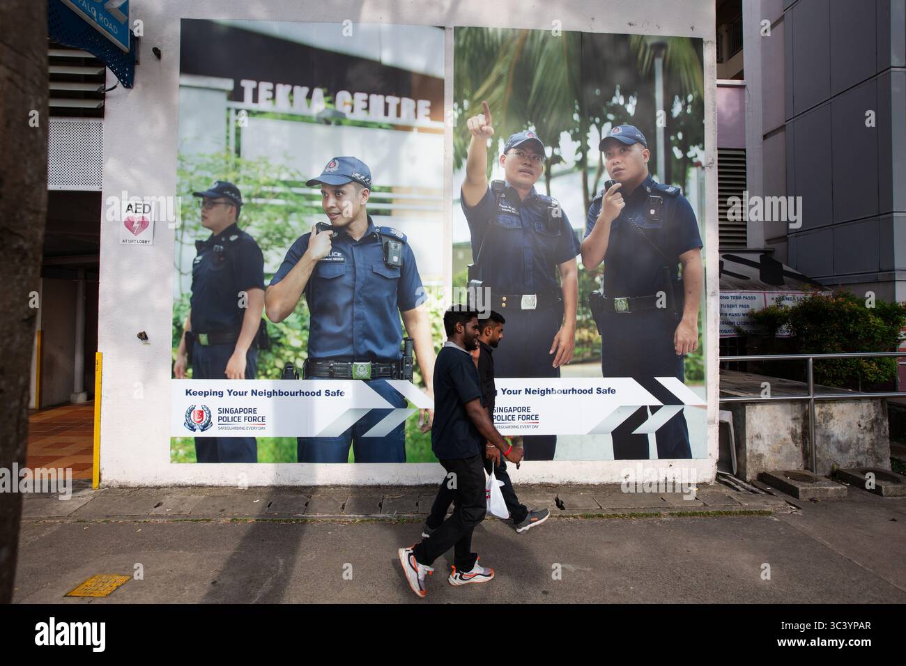 Straßenfotografie von zwei Indianern, die am Poster der Polizei vorbeigingen. Little India, Singapur Stockfoto