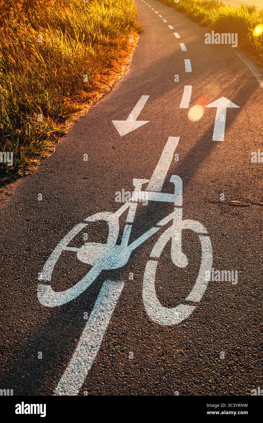 Fahrradspurschild auf Asphaltstraße bei Sonnenuntergang im Sommer, selektiver Fokus Stockfoto