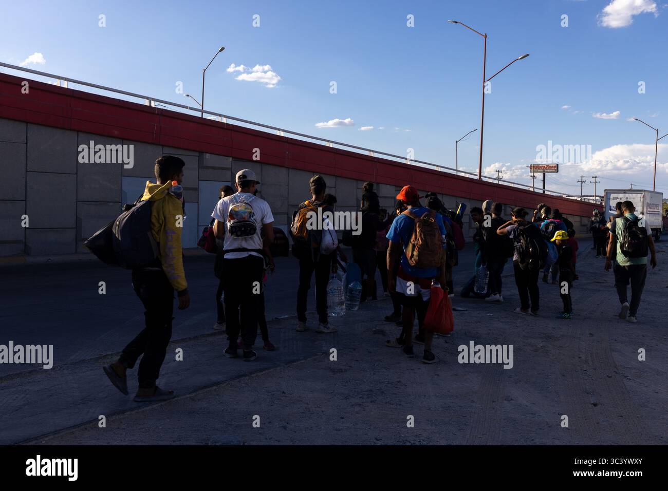 Migranten bewegen sich in der Nähe einer Straßenunterführung von Ciudad Juarez, was die Herausforderungen der Grenzmigration widerspiegelt. Stockfoto