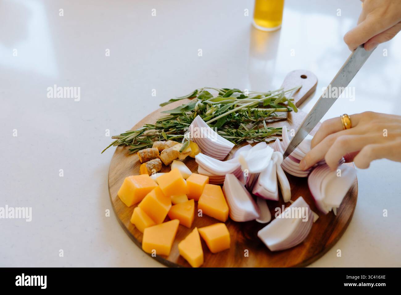 Der Koch hackt frische Zwiebeln und Butternusskürbis-Suppe Stockfoto