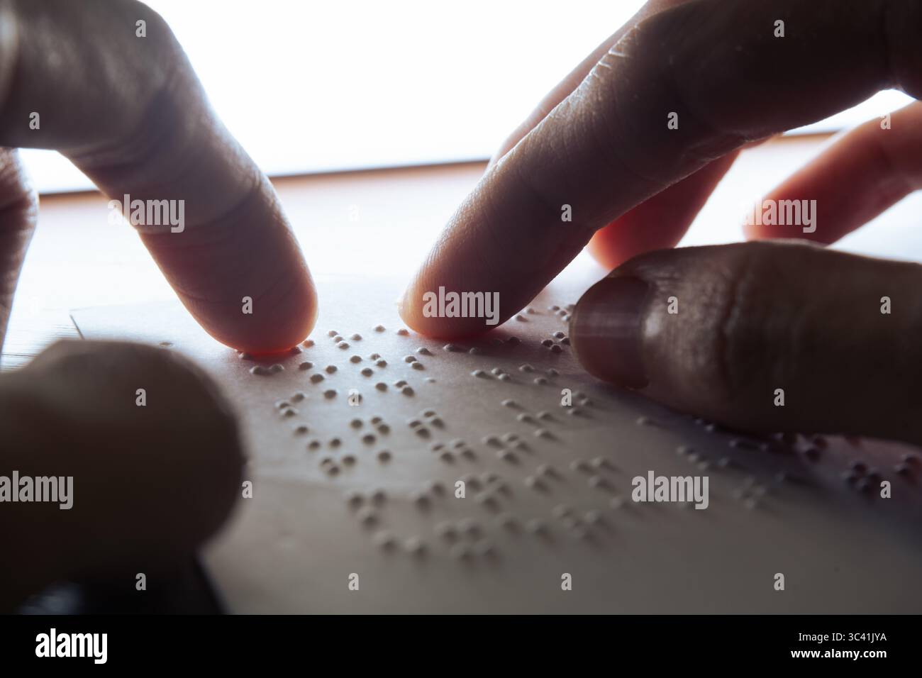 Sehbehinderte Menschen lesen mit ihren Fingerspitzen Braille auf Papier. Der Text auf dem Papier ist ein Dummy-Lorem-ipsum-Text. Stockfoto