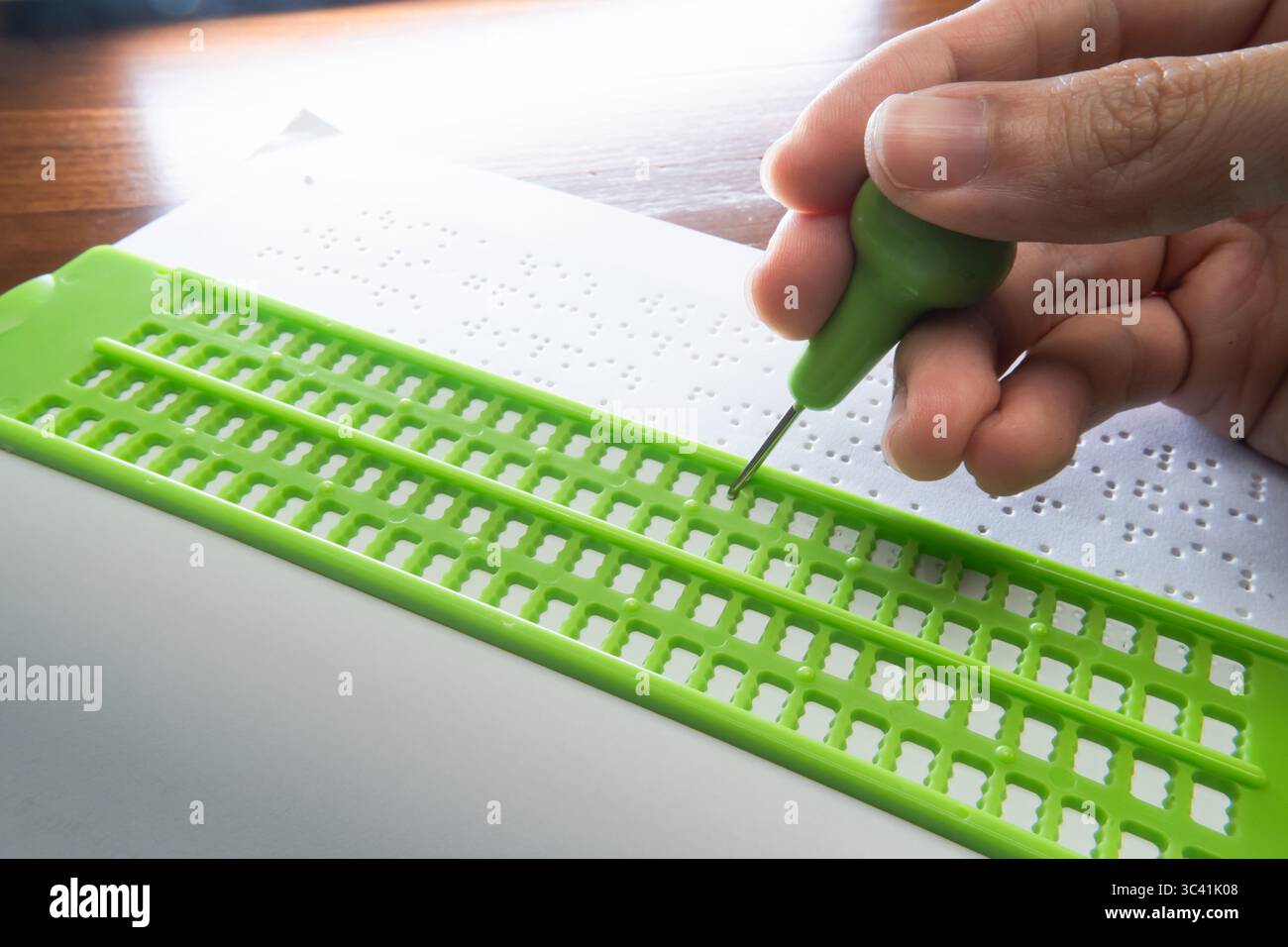 Schreiben Sie Braille mit Braille Schiefer und Stift. Der Text auf dem Papier ist ein Dummy-Lorem-ipsum-Text. Stockfoto