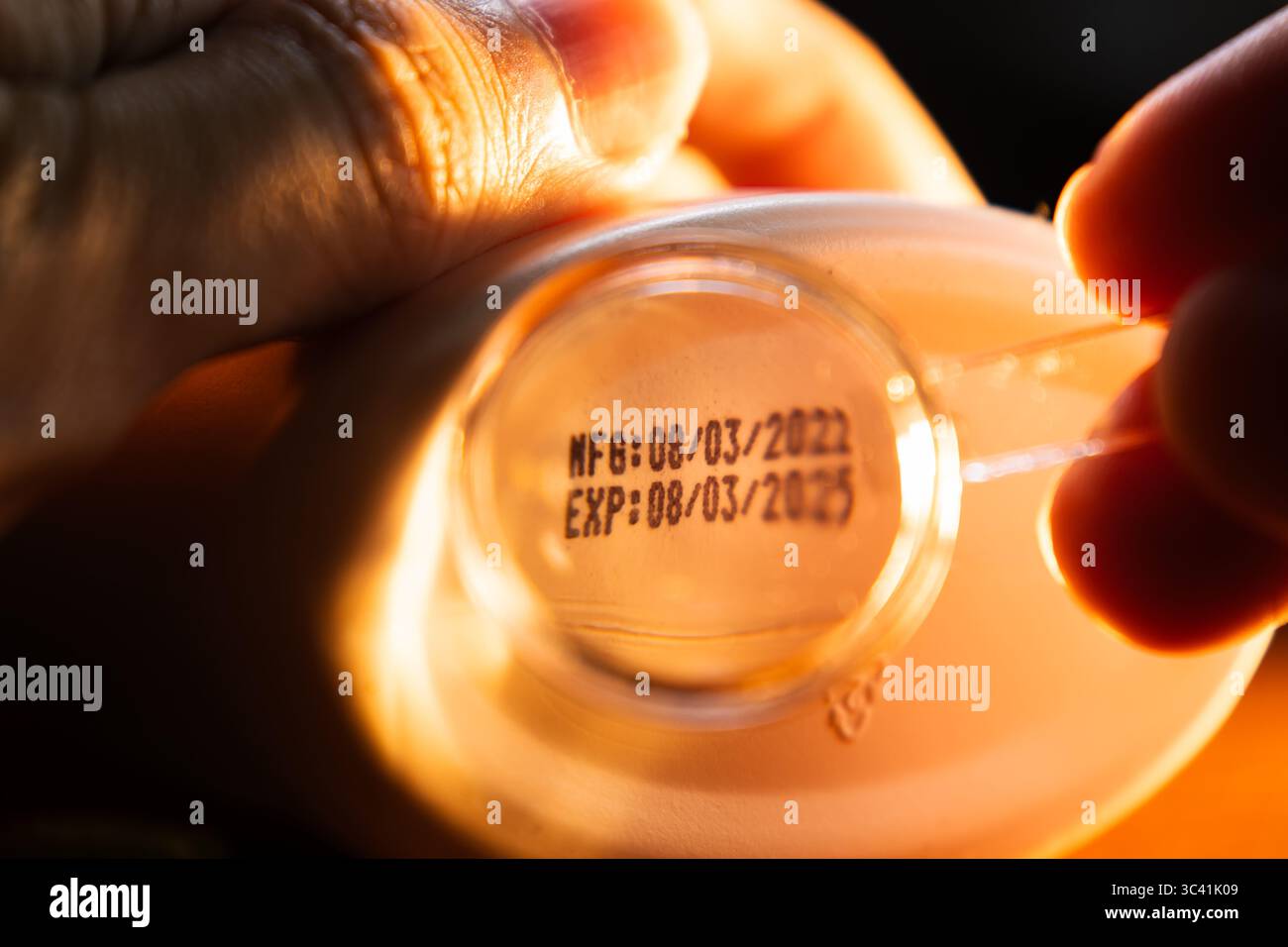 Lesen des kleinen Textes des Herstellungsdatums und des Ablaufdatums auf der Unterseite des Produkts mit Vergrößerungsglas Stockfoto