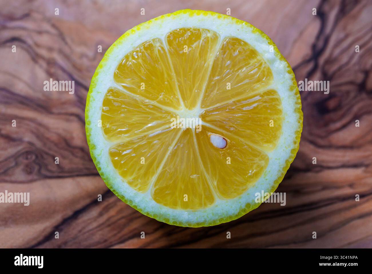 Geschnittene Zitrone auf einem Olivenholzbrett, Deutschland. Aufgeschnittene Zitrone liegt auf einem Olivenholzbrett, Deutschland. Stockfoto