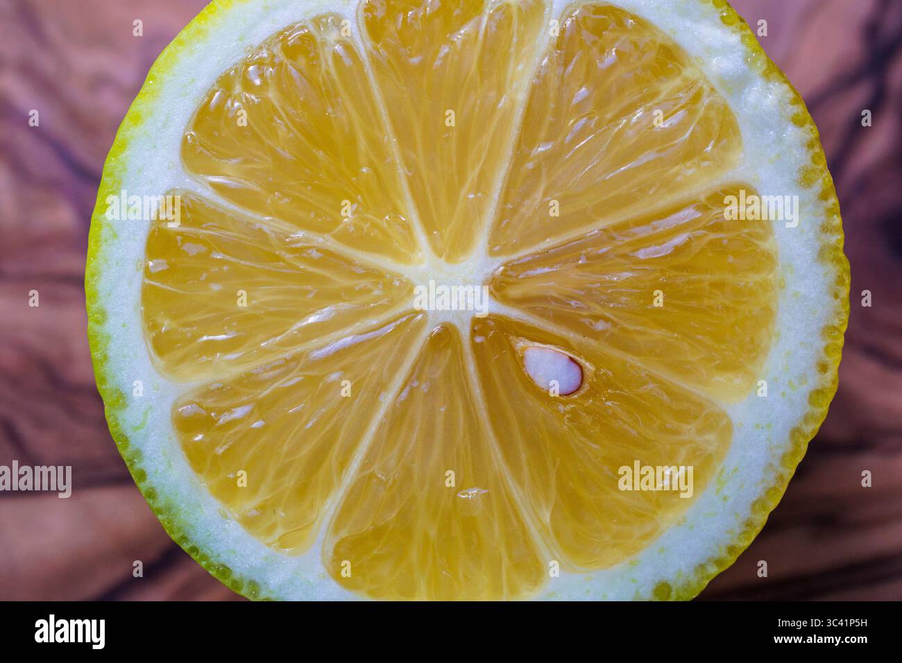 Geschnittene Zitrone auf einem Olivenholzbrett, Deutschland. Aufgeschnittene Zitrone liegt auf einem Olivenholzbrett, Deutschland. Stockfoto