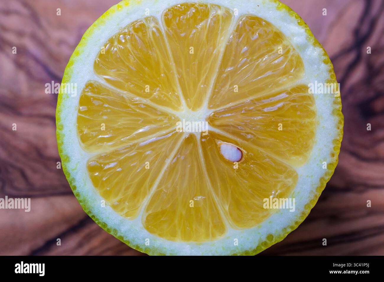 Geschnittene Zitrone auf einem Olivenholzbrett, Deutschland. Aufgeschnittene Zitrone liegt auf einem Olivenholzbrett, Deutschland. Stockfoto