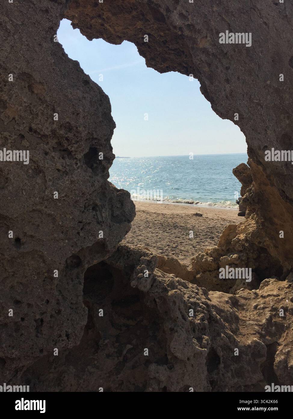 Atemberaubende Aussicht auf einen Sandstrand und den Horizont des Persischen Golfs, eingerahmt von einer natürlichen felsigen Höhle in Qeshm, ideal für Reisen und Naturfotografie Stockfoto