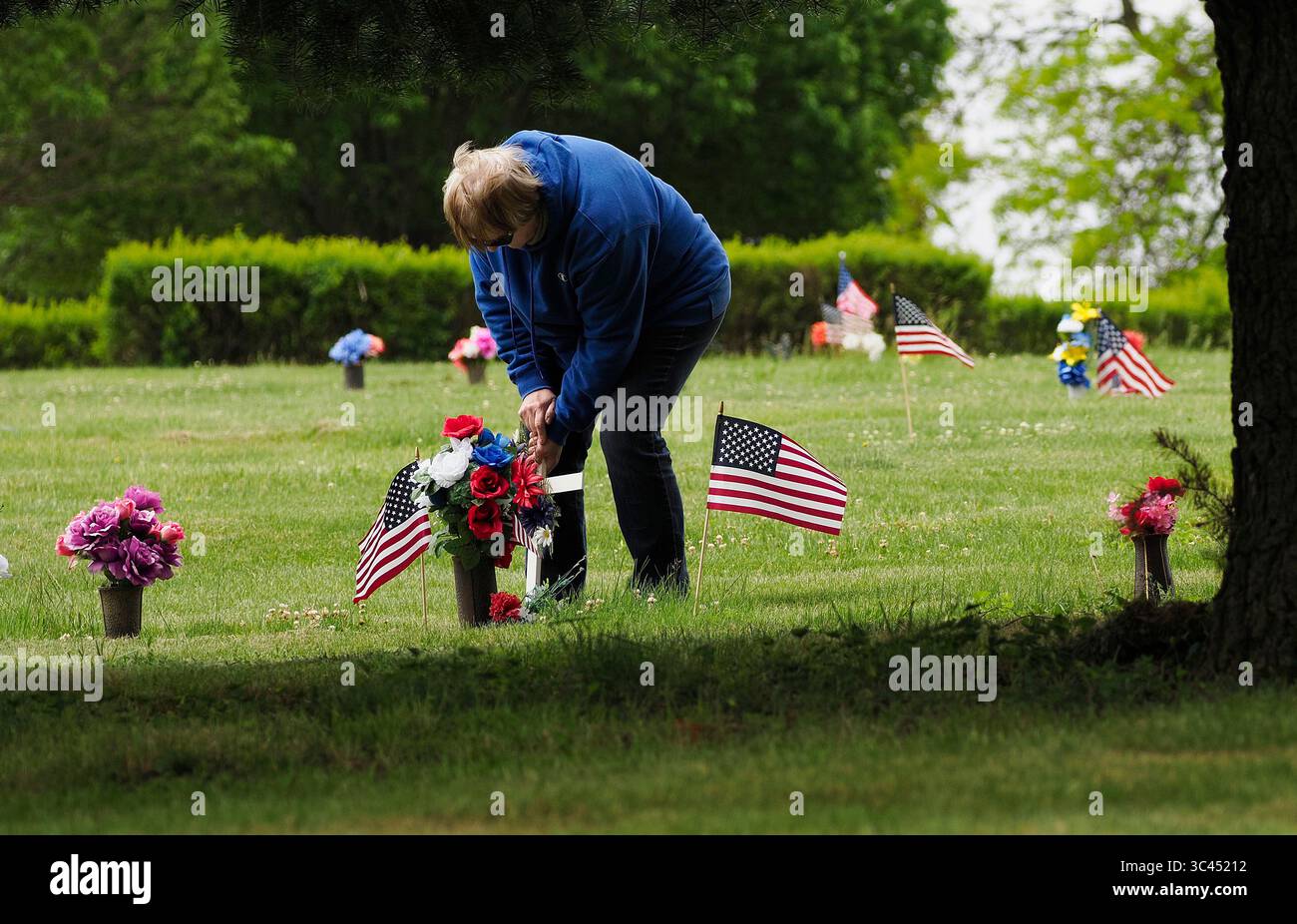28. Mai 2021, SIOUX CITY, IOWA, USA: CAROL WASHBURN von des Moines platziert ein Kreuz neben einer kleinen amerikanischen Flagge auf dem Grab eines Familienmitglieds auf dem Memorial Park Cemetery in Sioux City, Iowa Samstag, 29. Mai 2021. Washburn wuchs in einer kleinen Gemeinde Nebraska auf, direkt gegenüber dem Missouri River von Sioux City. Während der Woche brachten die örtlichen Strafverfolgungsbehörden und Mitglieder der Iowa Air National Guard und der Army National Guard kleine amerikanische Flaggen auf die Gräber von Veteranen. (Bild: © Jerry Mennenga/ZUMA Wire) Stockfoto