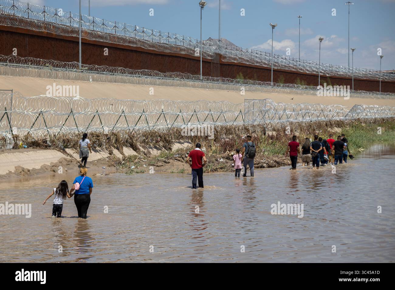 Die Menschen bewegen sich in einem Fluss an der befestigten Grenze zu Ciudad Juarez inmitten von Migrationsproblemen. Stockfoto