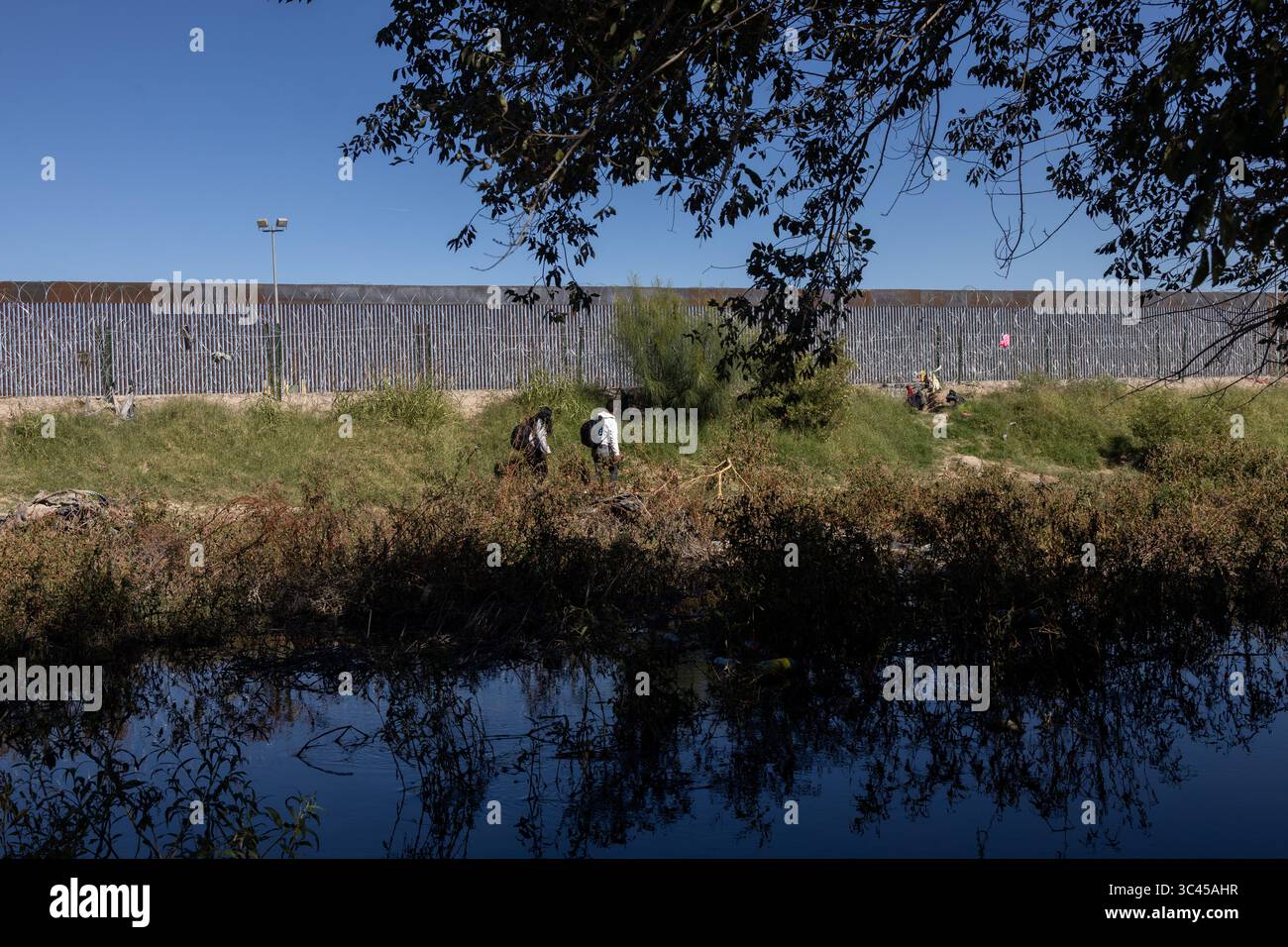 Menschen versammeln sich am hoch aufragenden Grenzzaun in Ciudad Juarez, einem ergreifenden Symbol für Migrationsherausforderungen. Stockfoto