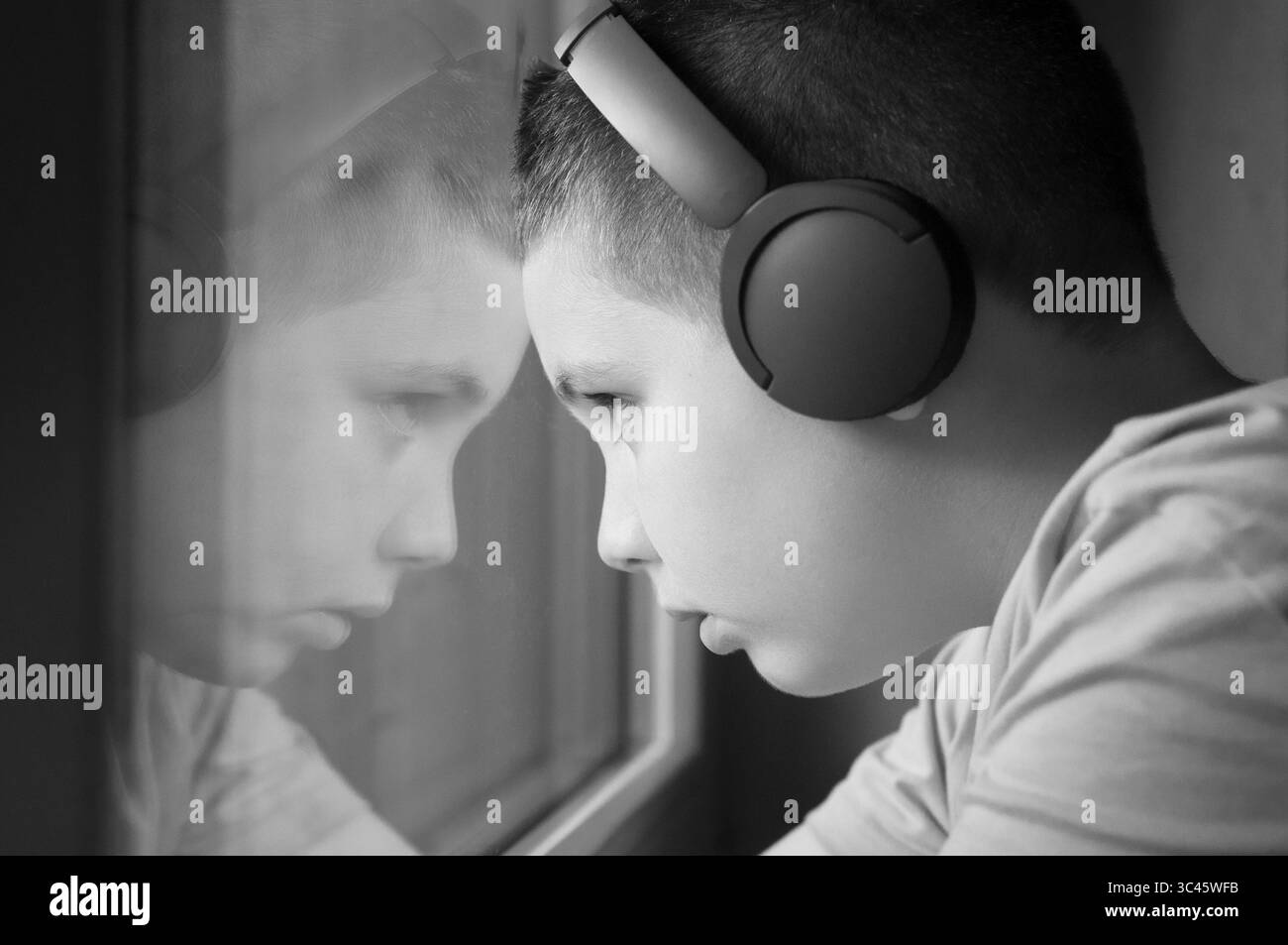 Junge, der Musik über Kopfhörer hört und aus dem Fenster blickt Stockfoto