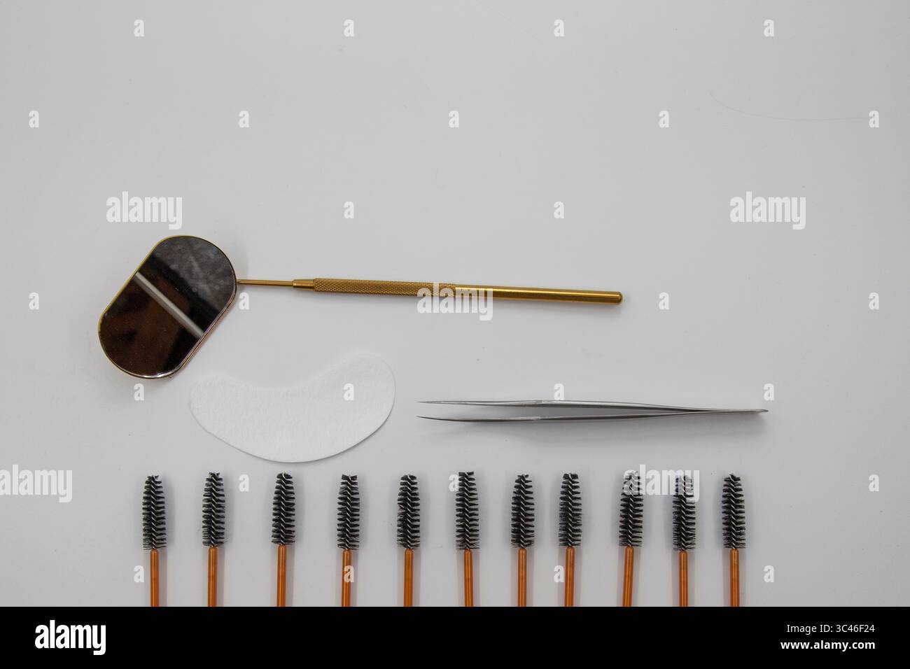 Satz professioneller Wimpernverlängerungswerkzeuge einschließlich Pinsel, Pinzette, Augenpflaster und Spiegel auf weißem Hintergrund. Stockfoto