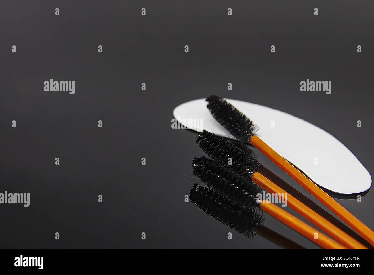Professionelle Wimpernverlängerungsbürsten und Unteraugenflecken auf schwarzem Hintergrund. Werkzeuge für Wimpernpflege, Schönheitssalon und Make-up-Verfahren. Stockfoto