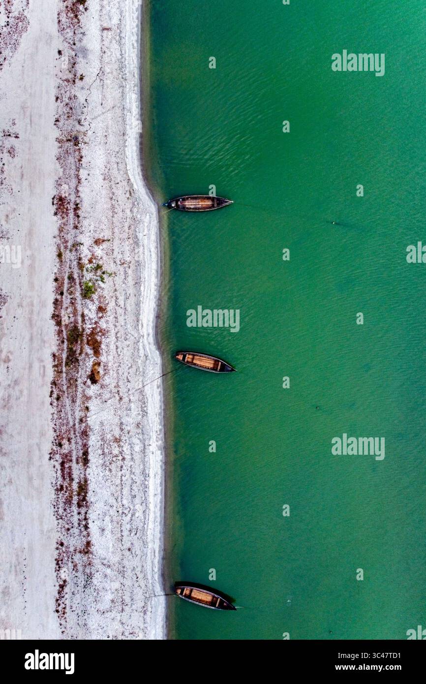 Aus der Vogelperspektive auf Boote, die am Rand liegen, wo der Sandstrand auf das türkisfarbene Wasser trifft, Cherson Oblast, Ukraine. Stockfoto