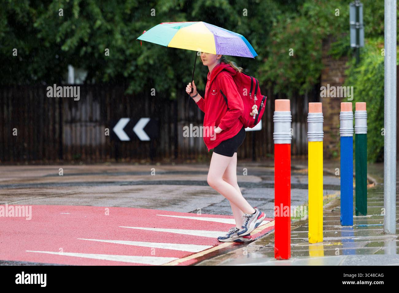 11-jähriges Mädchen/Schüler überquert die Straße/Straße mit farbigen Verkehrspollern in Form von Bleistift/Bleistiften. Twickenham. London. UK. (145). Stockfoto