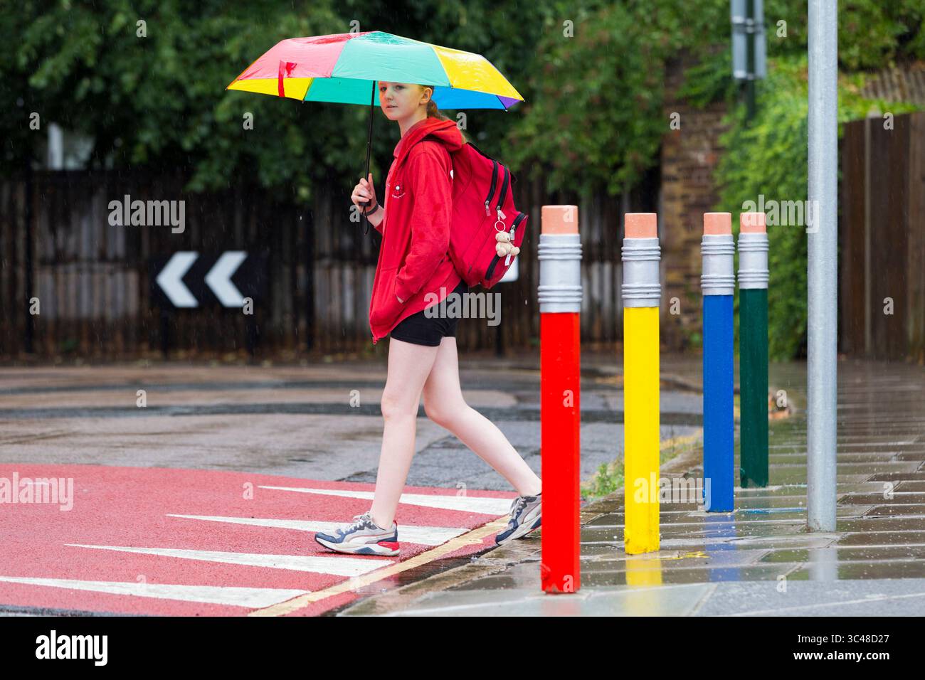 11-jähriges Mädchen/Schüler überquert die Straße/Straße mit farbigen Verkehrspollern in Form von Bleistift/Bleistiften. Twickenham. London. UK. (145). Stockfoto