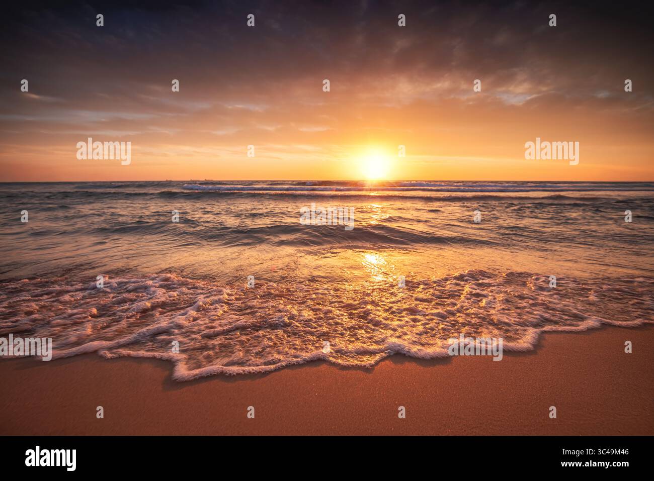 Atemberaubender Sonnenuntergang am Strand mit leuchtenden Farben und beruhigenden Wellen Stockfoto