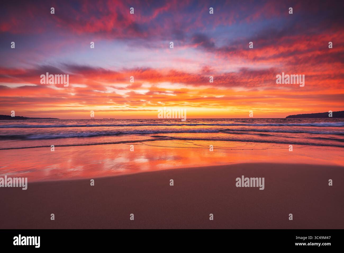 Atemberaubender Sonnenuntergang am Strand mit leuchtenden Farben und beruhigenden Wellen Stockfoto