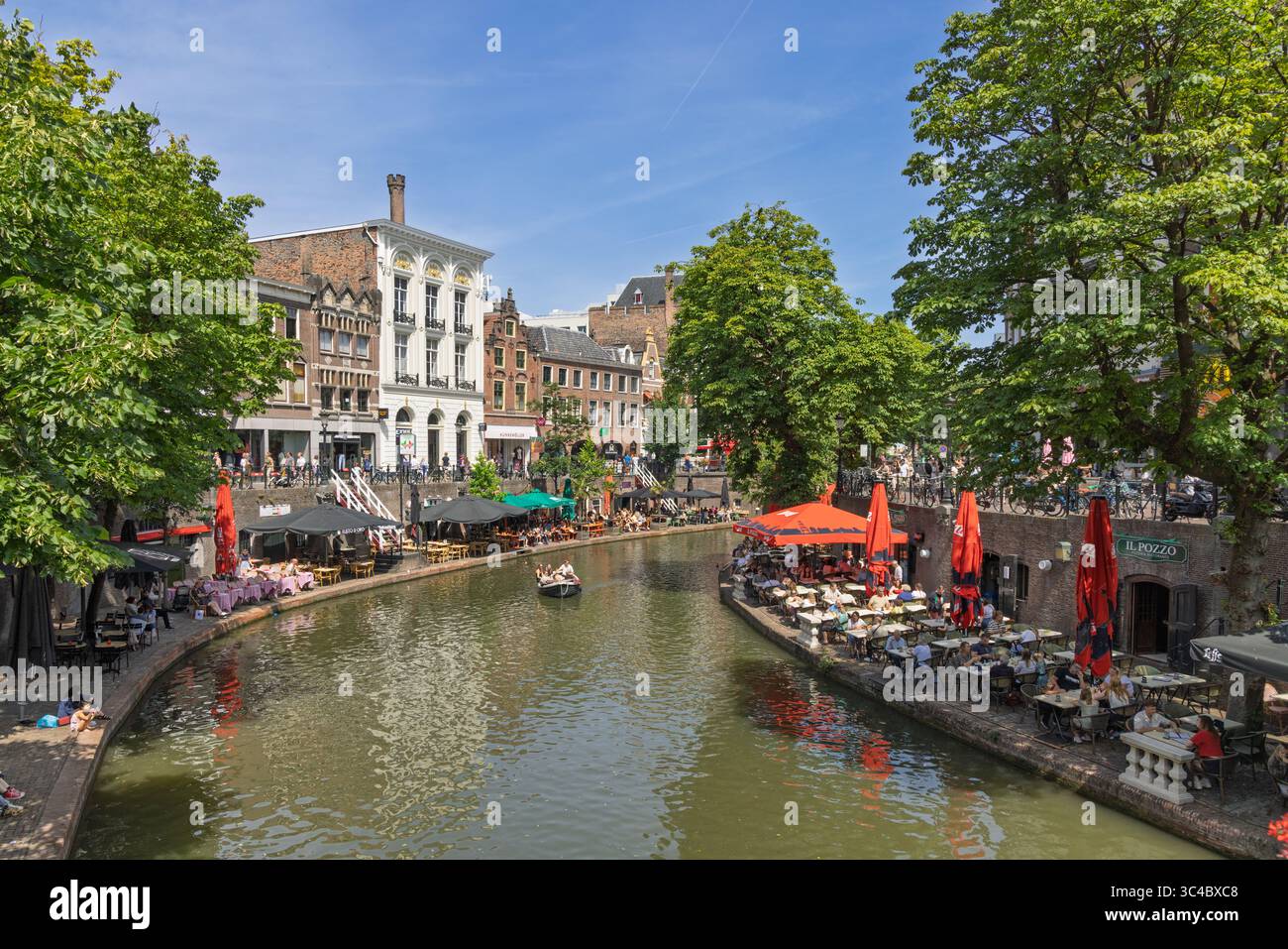 Eine lebhafte Szene entlang des Oude Gracht-Kanals in Utrecht, Niederlande, wo die Menschen Cafés im Freien genießen und eine Bootsfahrt auf dem Wasser Unternehmen. Utrecht, Neth Stockfoto