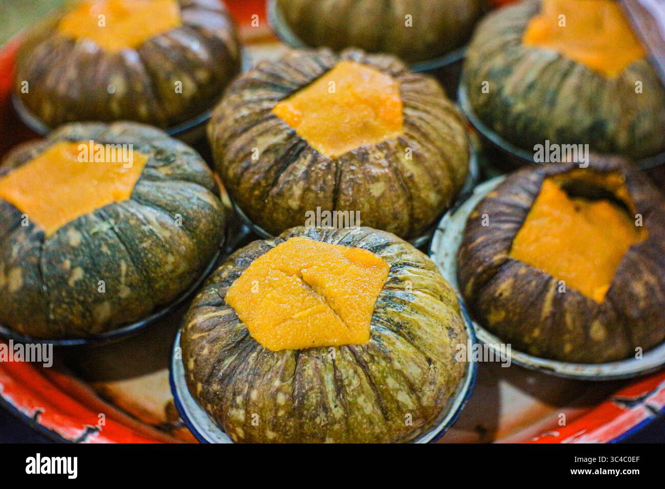 Thailändisches Kürbis-Pudding-Dessert namens Sangkaya. Eine süße Kombination aus Kokos-Ei-Pudding in gedämpftem Kürbis, gefunden in Street Food. Stockfoto
