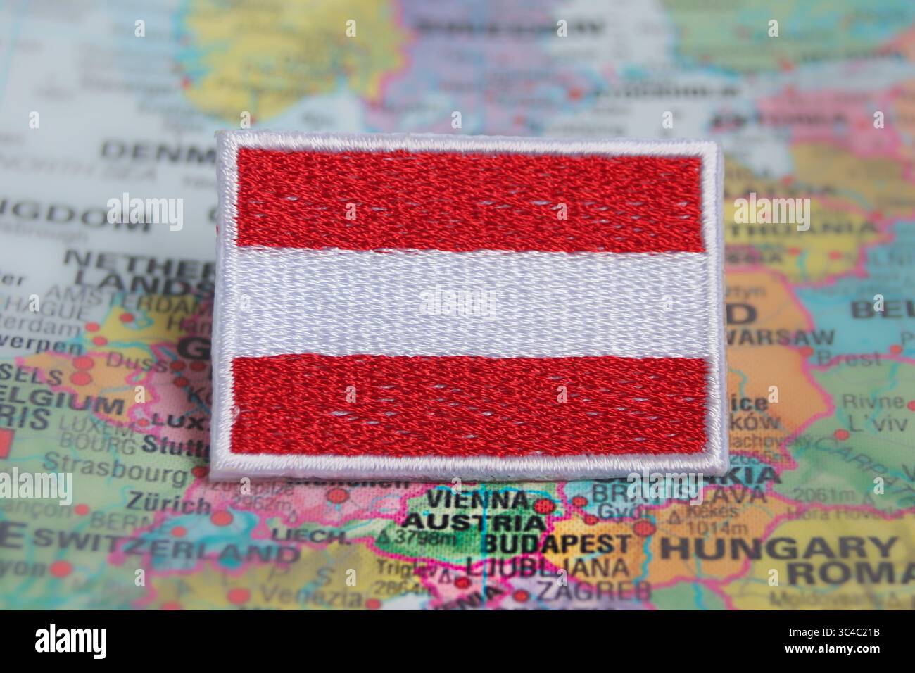 Österreichische Flagge im Öko-Stil aus Textil auf der Weltkarte am Standort Österreichs platziert. Symbol für grünen Tourismus und nachhaltiges Reisen. Stockfoto