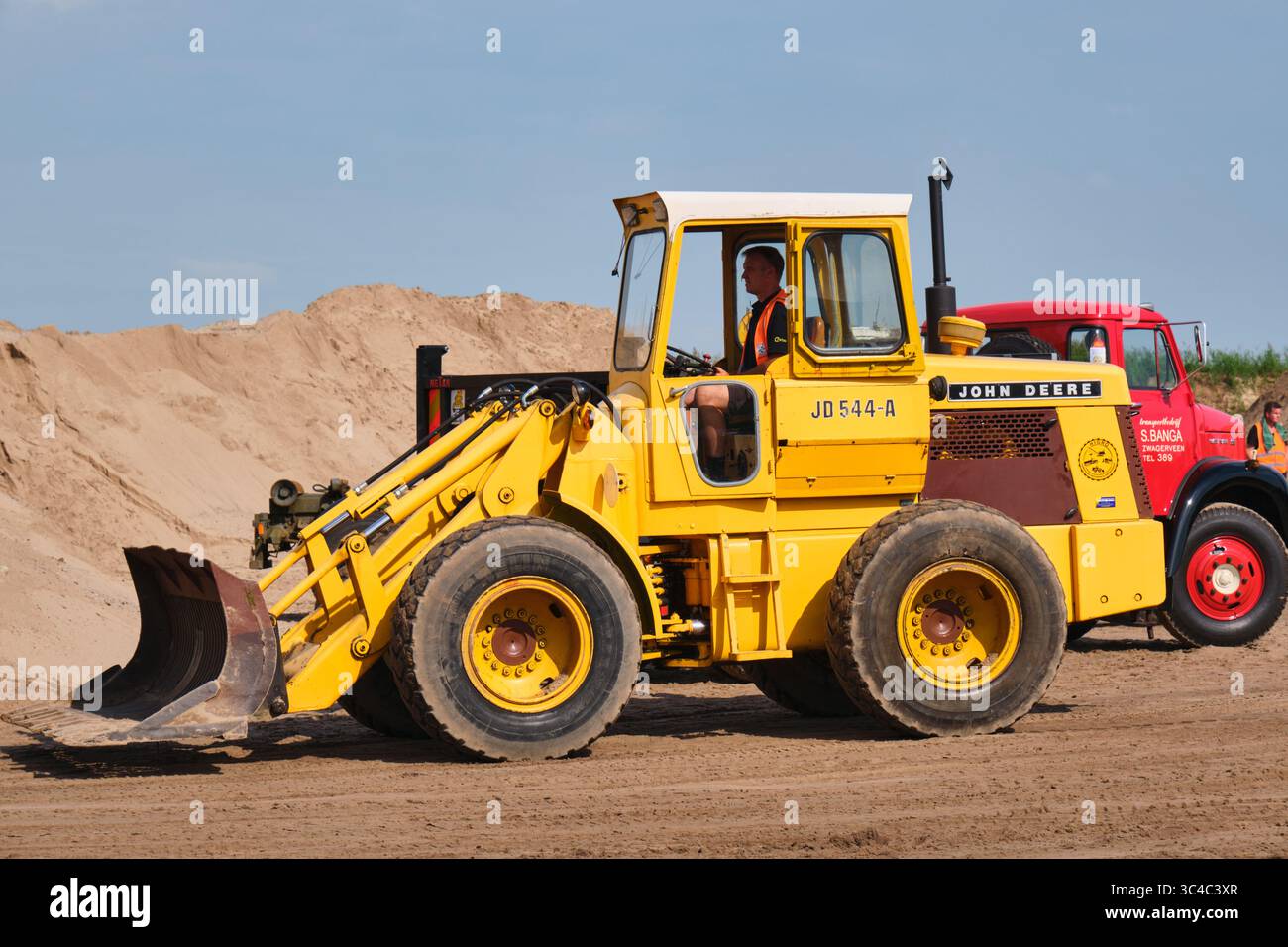 7. September 2024 – Aldtsjerk-Niederlande: Der alte John Deere 544-A Radlader aus den 1970er Jahren beladen einen alten Kipplader in einem Sandbruch während eines Stockfoto