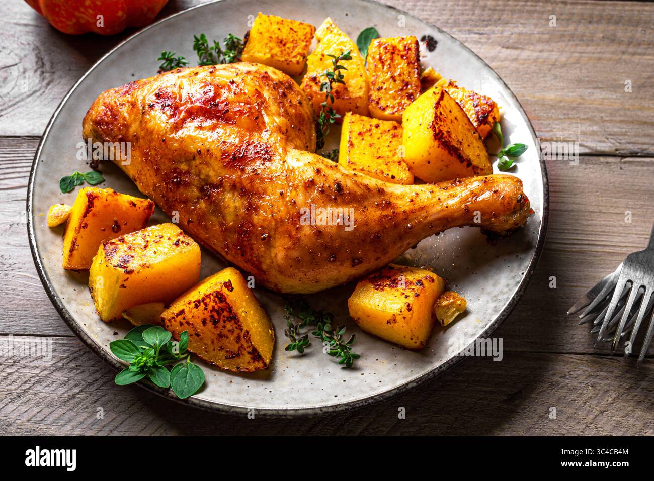 Gebratenes Hähnchenviertel und Kürbis mit Knoblauch und Kräutern auf Teller Nahaufnahme. Im Ofen gebackener Kürbis und truthahn, saisonales Herbstgericht. Stockfoto