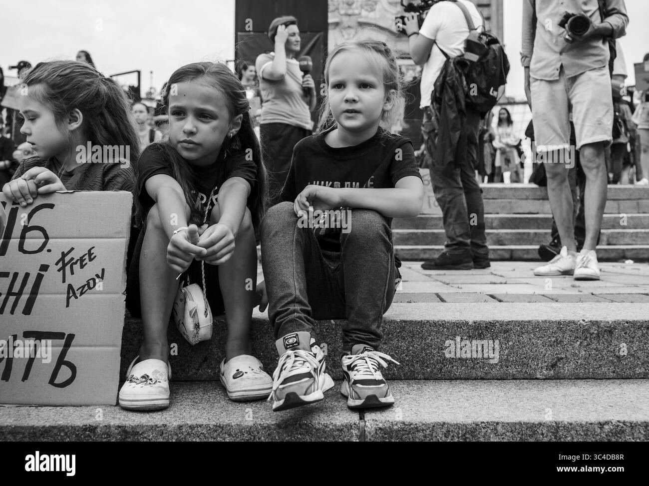 Kiew, Ukraine - 28. Juli 2025: Ukrainische Kinder sitzen während einer Demonstration zu Ehren der Opfer des Massakers im Gefängnis Oleniwka auf Stufen und halten Schilder für das Asow-Regiment. In der Nacht vom 28. Auf den 29. Juli 2022 beschossen die Russen die Gefängniskolonie Wolnovakha in der Nähe des besetzten Oleniwka. Mindestens 53 ukrainische Gefangene aus Asovstal wurden bei dem Terroranschlag getötet und mehr als 130 verletzt. Quelle: ARTEM HVOZDKOV/Alamy Live News Stockfoto