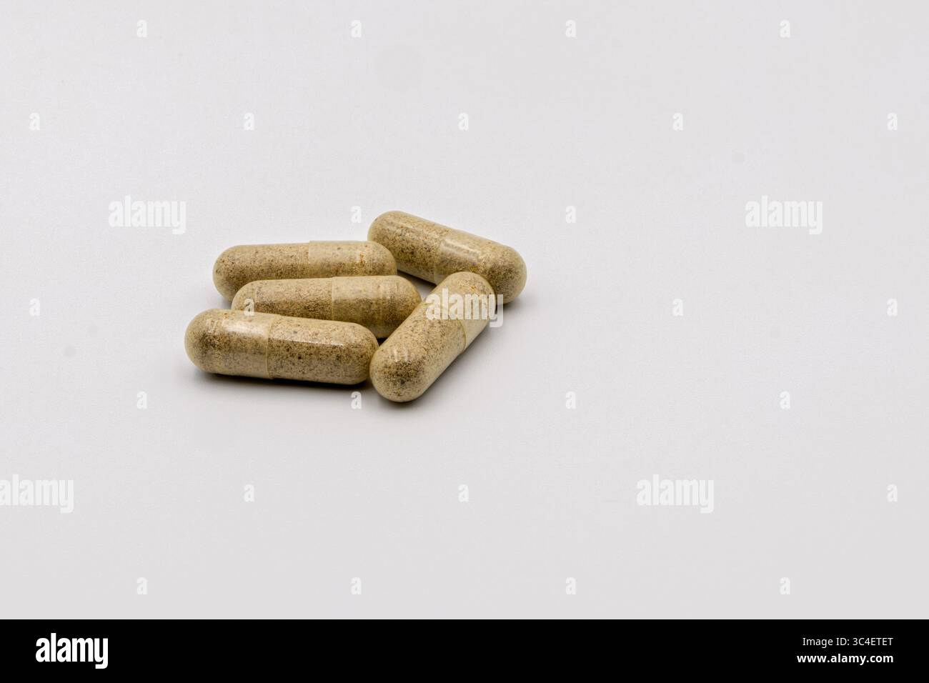 Fünf braune Naturkapseln, ordentlich auf einer sauberen, hellen Oberfläche angeordnet. Stockfoto