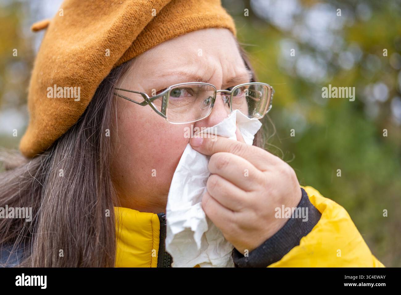Kranke reife Frau mit Gewebe, bläsender Nase, litt an Niesen, saisonale Allergie, Außenporträt, Erkältungssymptome, Niesen, Außenporträt, f Stockfoto