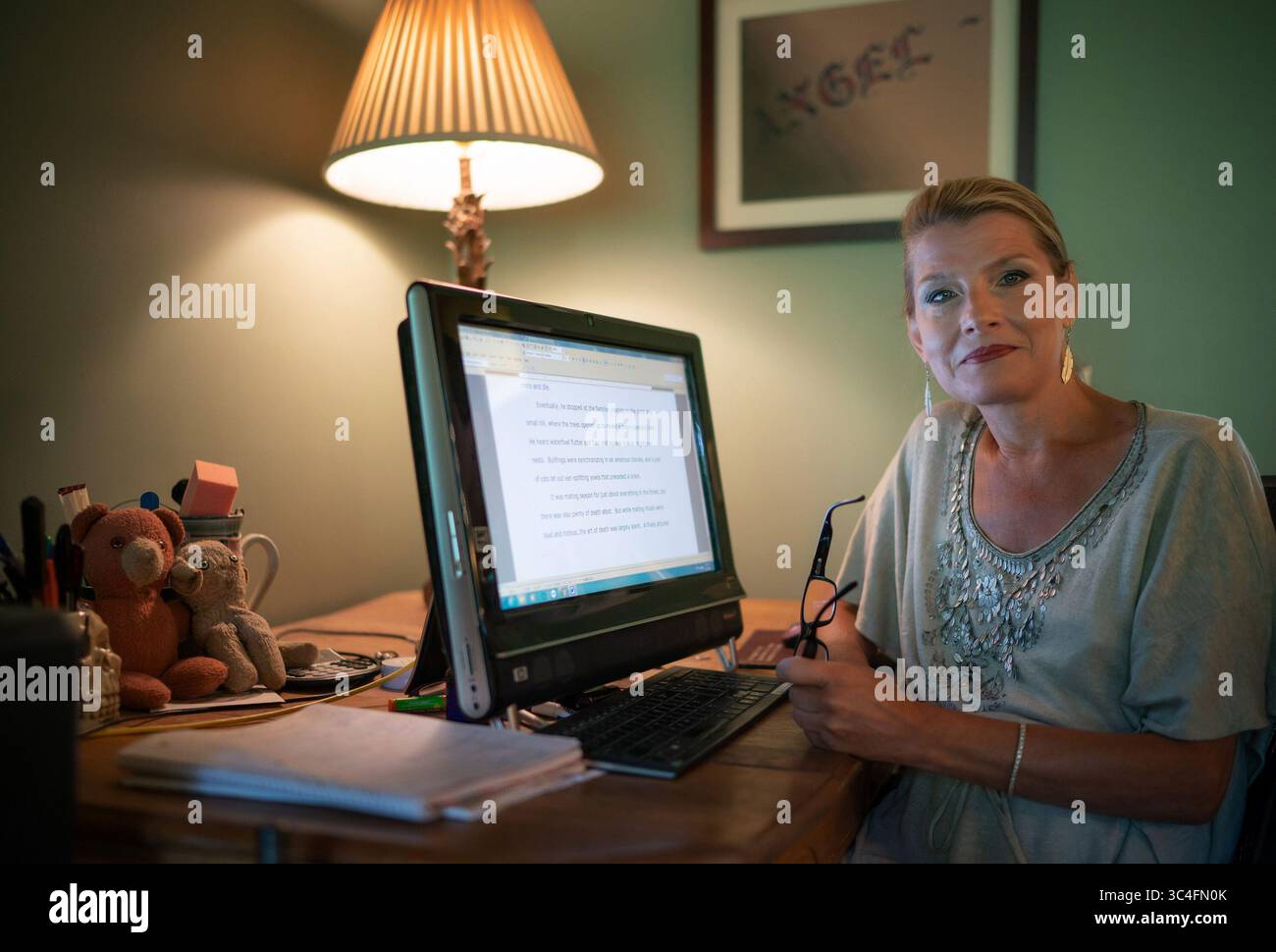 1. August 2018 – Marine auf St. Croix, MN, USA – Traci Lambrecht arbeitet an ihrem neuesten Buch an ihrem Schreibtisch direkt neben ihrer Küche mit den allgegenwärtigen Teddy und Lambie, ihren Kuschelspielzeugen aus der Kindheit. Eine Urne mit der Asche ihrer Mutter ist im Wohnzimmer hinter ihr. (Bild: © Glen Stubbe/TNS via ZUMA Wire) Stockfoto