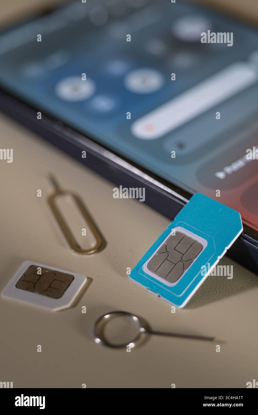 SIM-Fach und SIM-Karte neben einem Smartphone, bereit zum Einsetzen. Ideal für technische Blogs, Setup-Anleitungen für Smartphones, Reparaturservices oder Tutoren für Mobilgeräte Stockfoto