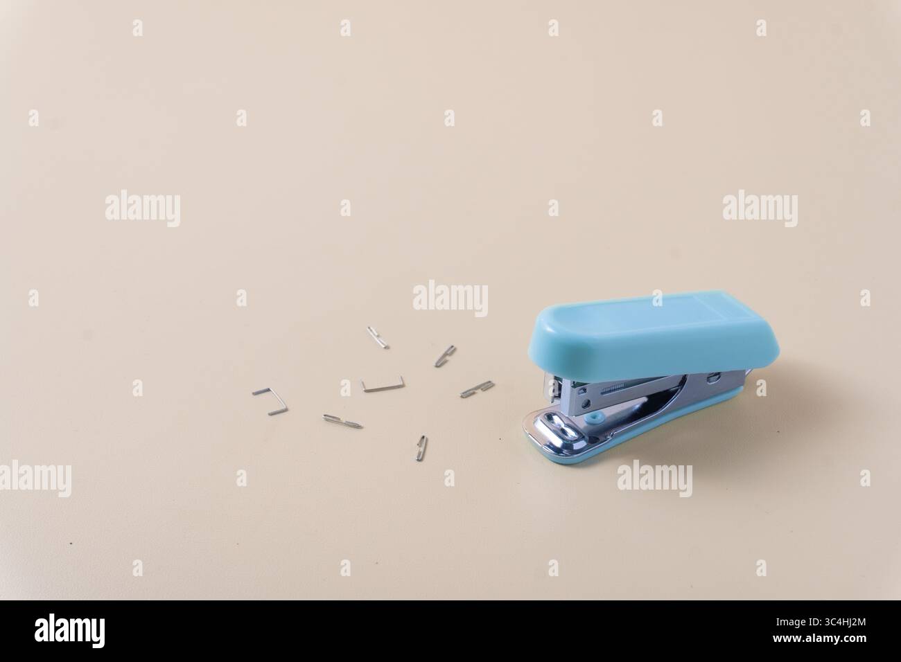 Ein Desktop-Hefter, umgeben von verstreuten Heftklammern auf einem Tisch. Erfasst eine geschäftige, leicht unordentliche Arbeits- oder Büroszene mit Nahaufnahmen Stockfoto