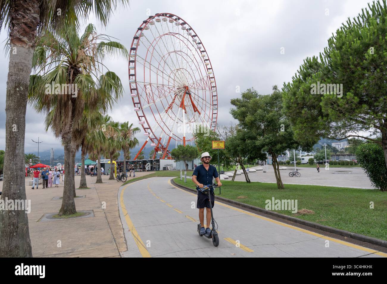 Besucher und Touristen fahren Elektroroller entlang eines speziellen Radweges an der Küste von Batumi an der Schwarzmeerküste von Georgien. Stockfoto