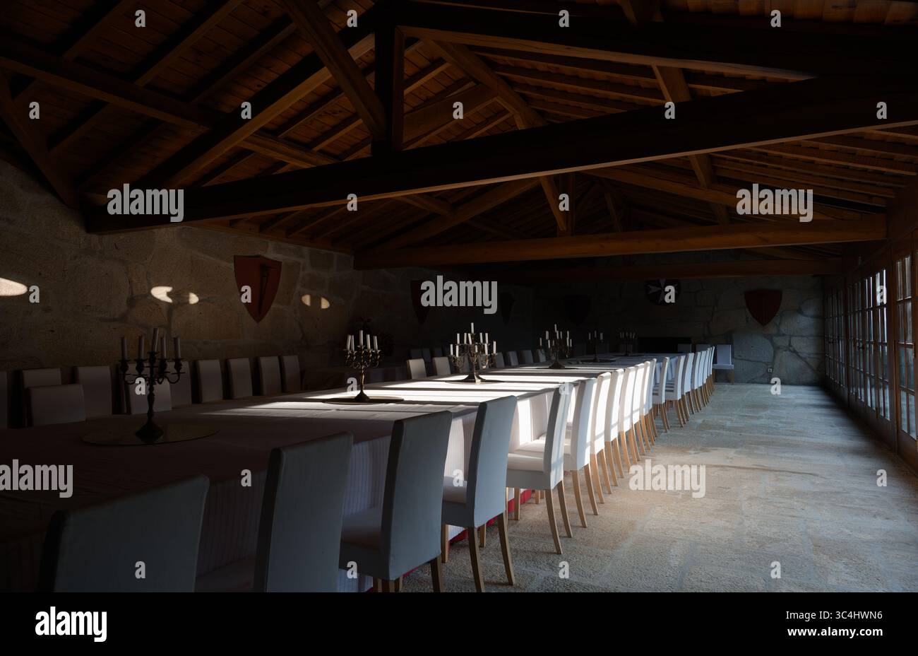 Eleganter Bankettsaal auf dem Calheiros-Platz, in dem Sonnenlicht über weiße Leinen- und Steinböden strömt Stockfoto