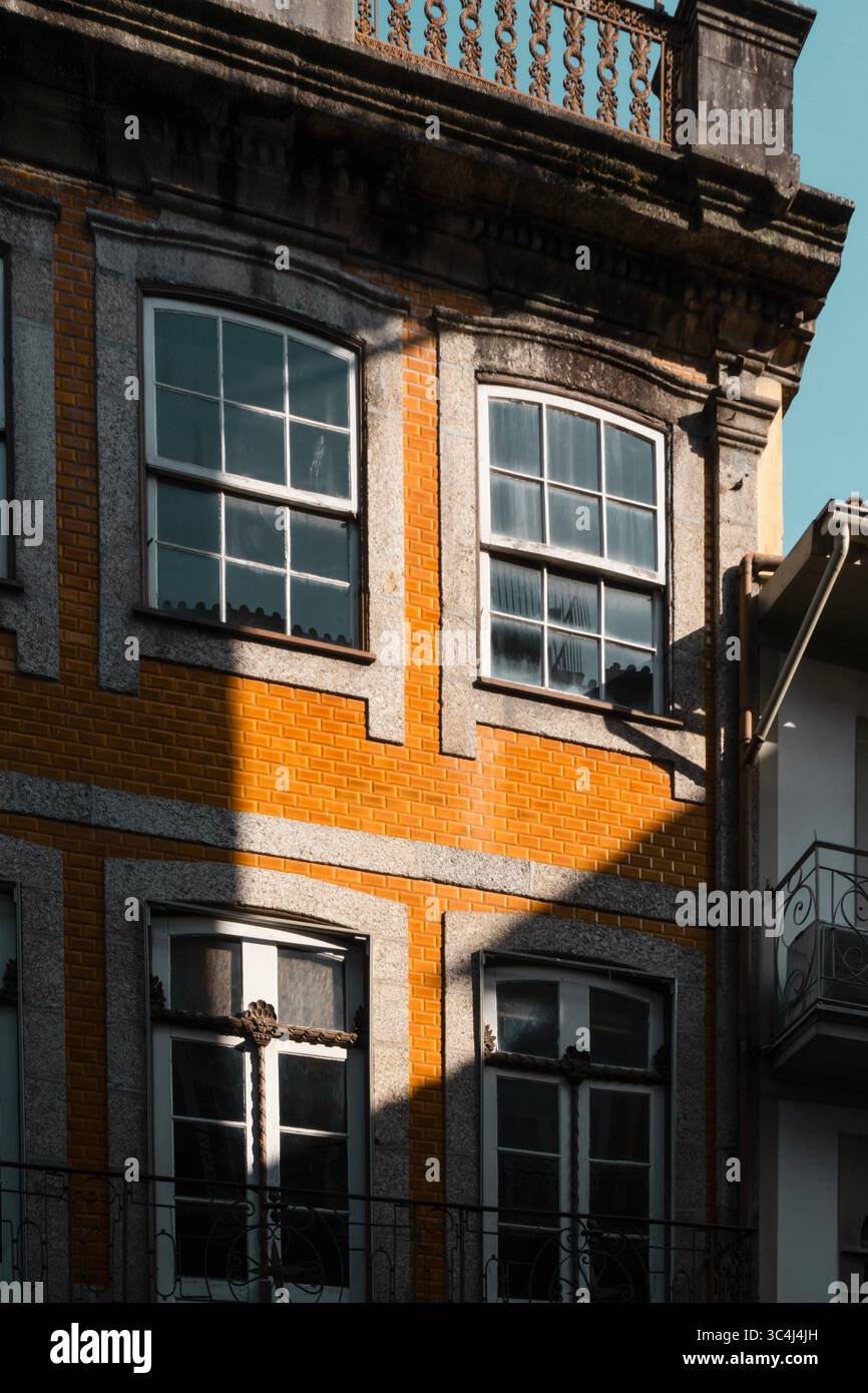 Traditionelle Portugiesische Architekturfassade Mit Orangefarbenen Ziegelsteinen Und Steindetails In Guimaraes. Historisches Gebäude, mehrstöckige Fenster, Heritage, Urban C Stockfoto