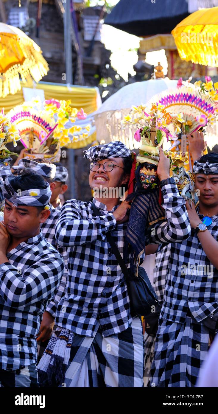 Junger balinesischer Mann lächelt während der traditionellen Zeremonie in Bali mit dem heiligen Opfer Stockfoto