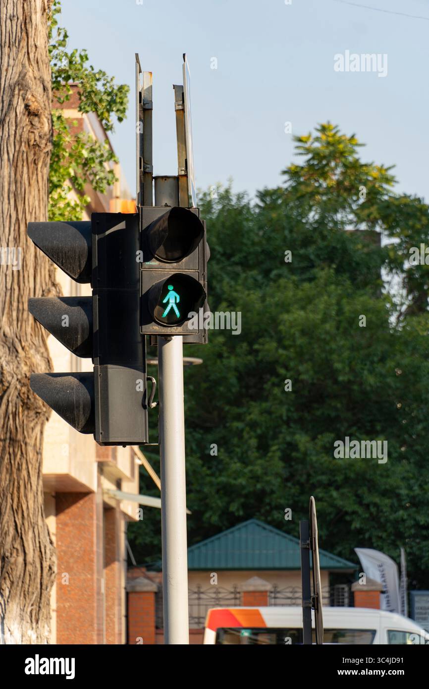 Nahaufnahme eines grünen Fußgängersignals an einer Ampel vor einem städtischen Hintergrund, das die Mobilität, den Transport und die öffentliche Sicherheit in der Stadt veranschaulicht Stockfoto
