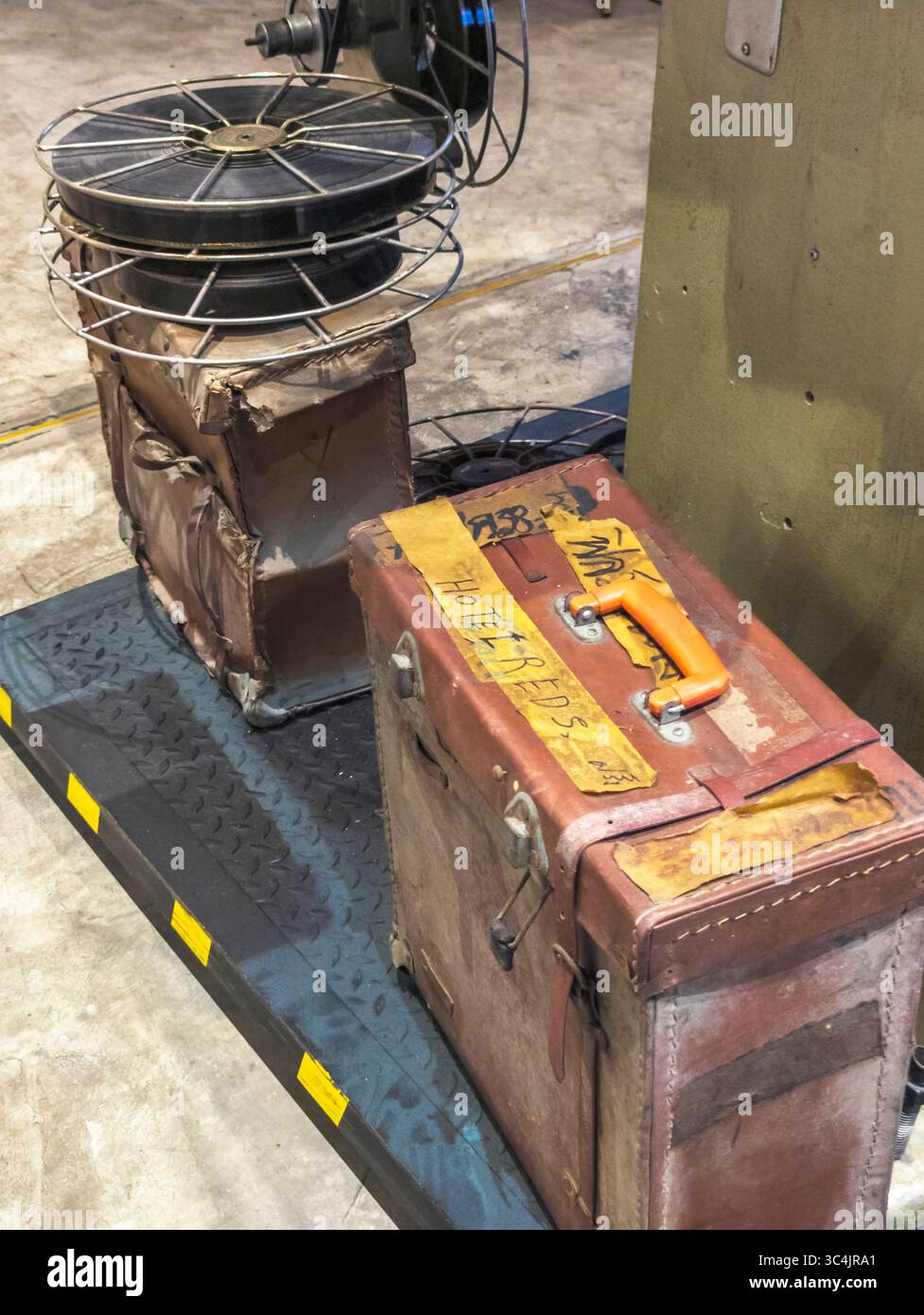 Bangkok, Thaialnd-Juli 04 2024: Großer professioneller Filmprojektor, umgeben von alten Rollen mit Film- und Vintage-Lederkoffer, im Hauptgebäude zu sehen Stockfoto