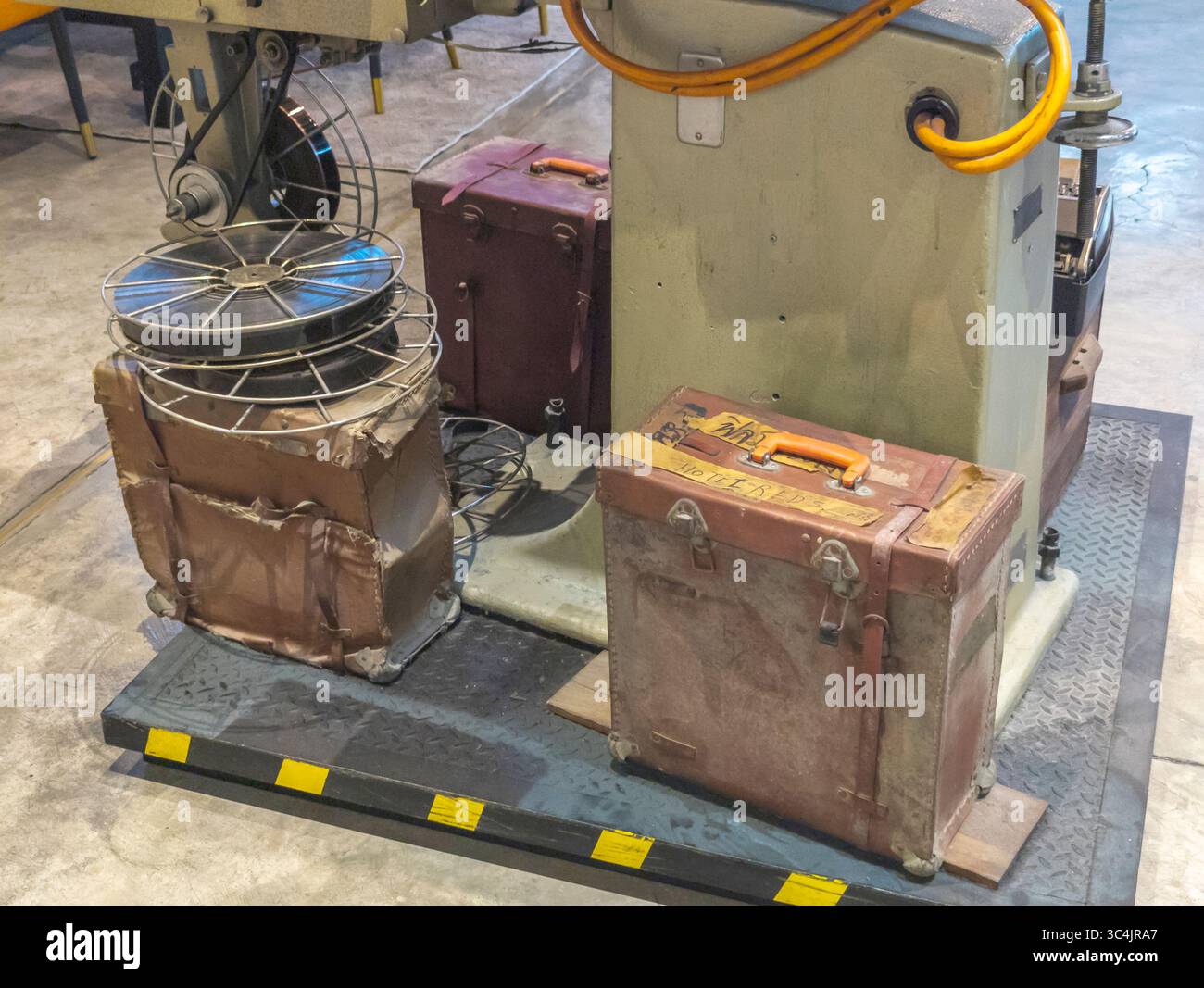 Bangkok, Thaialnd-Juli 04 2024: Großer professioneller Filmprojektor, umgeben von alten Rollen mit Film- und Vintage-Lederkoffer, im Hauptgebäude zu sehen Stockfoto