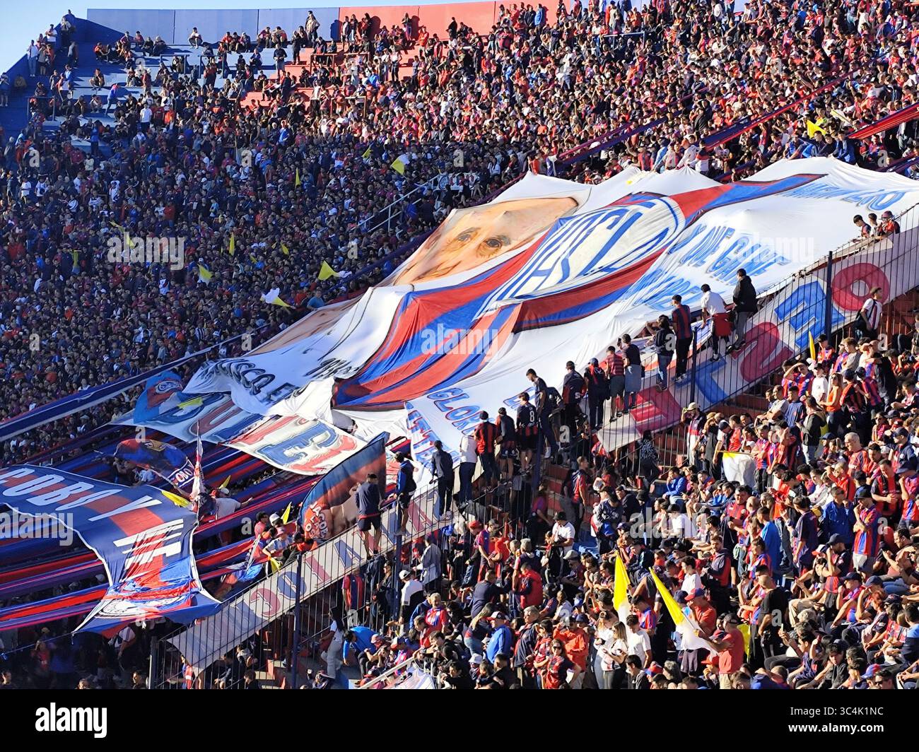 Anhänger von San Lorenzo zollen Papst Franziskus mit einer riesigen Flagge, die sein Porträt trägt, im Estadio Pedro Bidegain in Buenos Aires Tribut Stockfoto