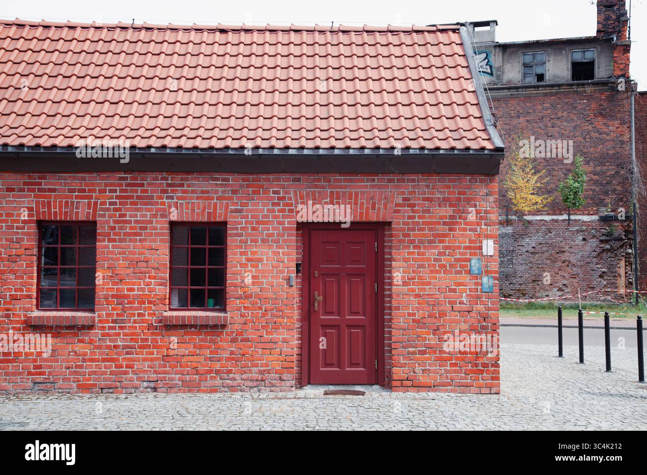 Kleines Versorgungsgebäude aus rotem Backstein mit Metallziegeldach, vor dem Hintergrund von Ruinen Stockfoto