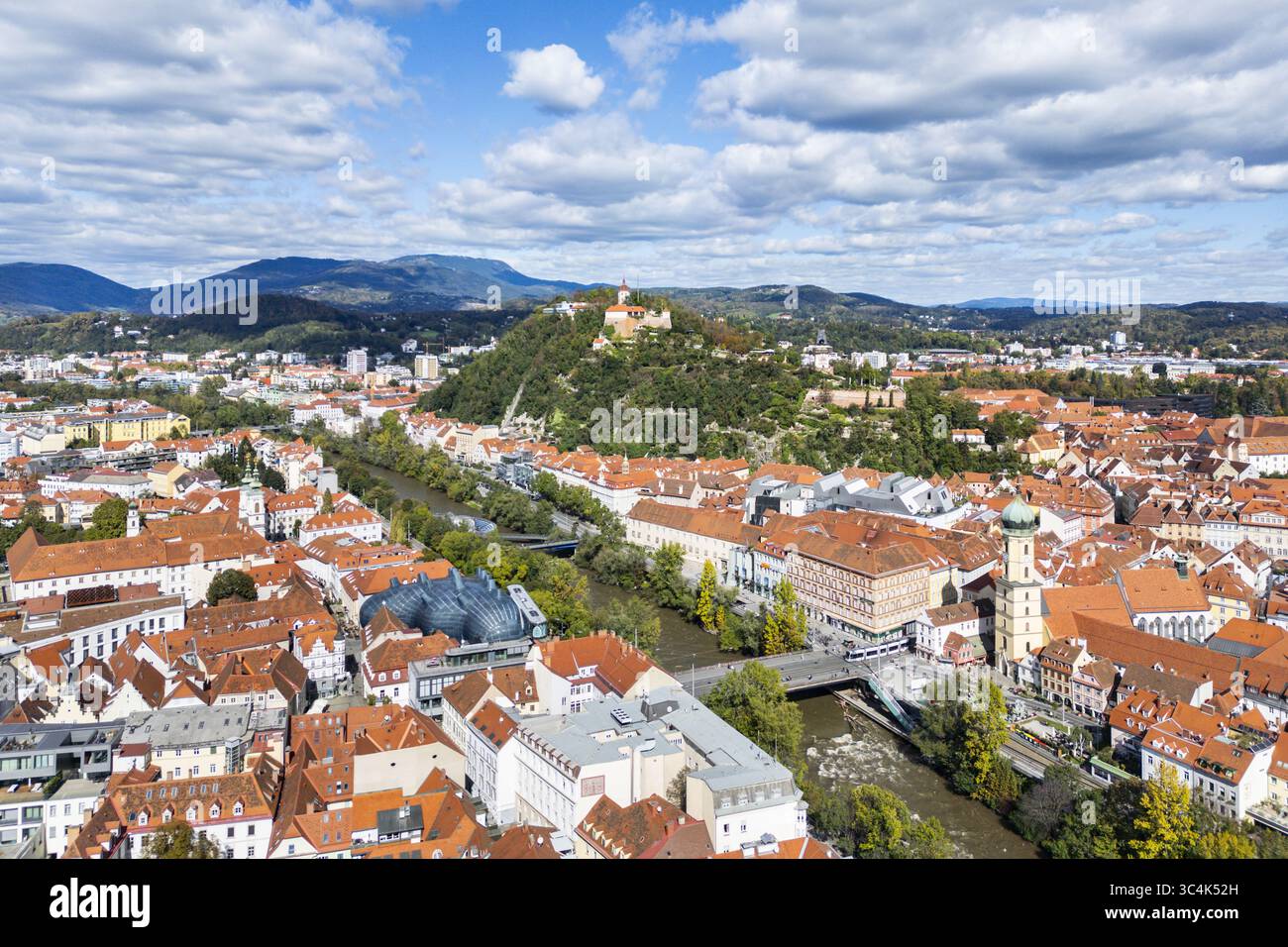 Aus der Vogelperspektive auf Graz und die Mur, die sich durch die Stadt schlängelt, mit Blick auf den Schlossberg und seinen historischen Uhrenturm, Graz, Steiermark, Österreich. Stockfoto
