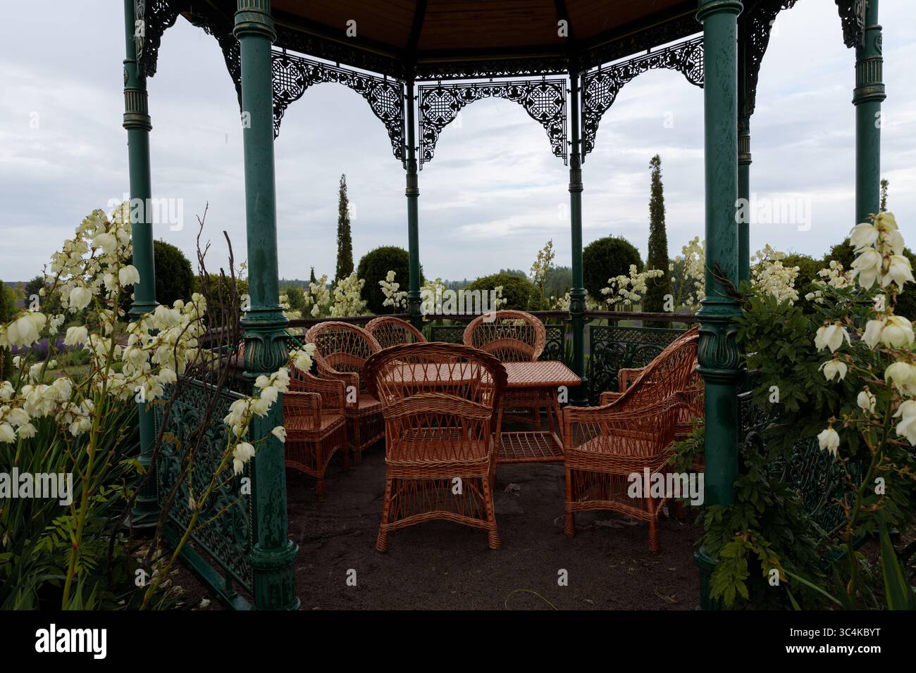 Bezaubernder Gartenlaube umgeben von üppigem Grün und wunderschönen weißen Blumen, perfekt zum Entspannen und Genießen der Schönheit der Natur Stockfoto