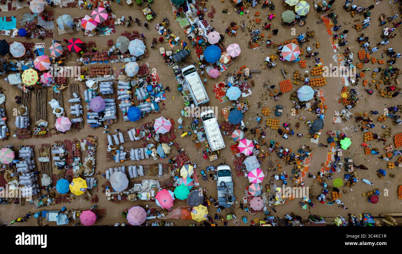 Aus der Vogelperspektive sehen Sie pulsierende Regenschirme auf dem geschäftigen Farin Gada Markt, im Kontrast zu den Erdtönen des Bodens, Jos, Plateau, Nigeria. Stockfoto
