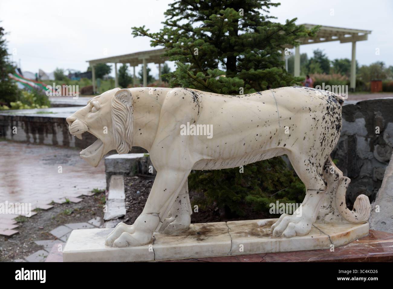 Prächtige Marble Lion Skulptur: Eine atemberaubende Darstellung der antiken Kunst in Stein, die Stärke und Majestät in einem öffentlichen Park festnimmt Stockfoto