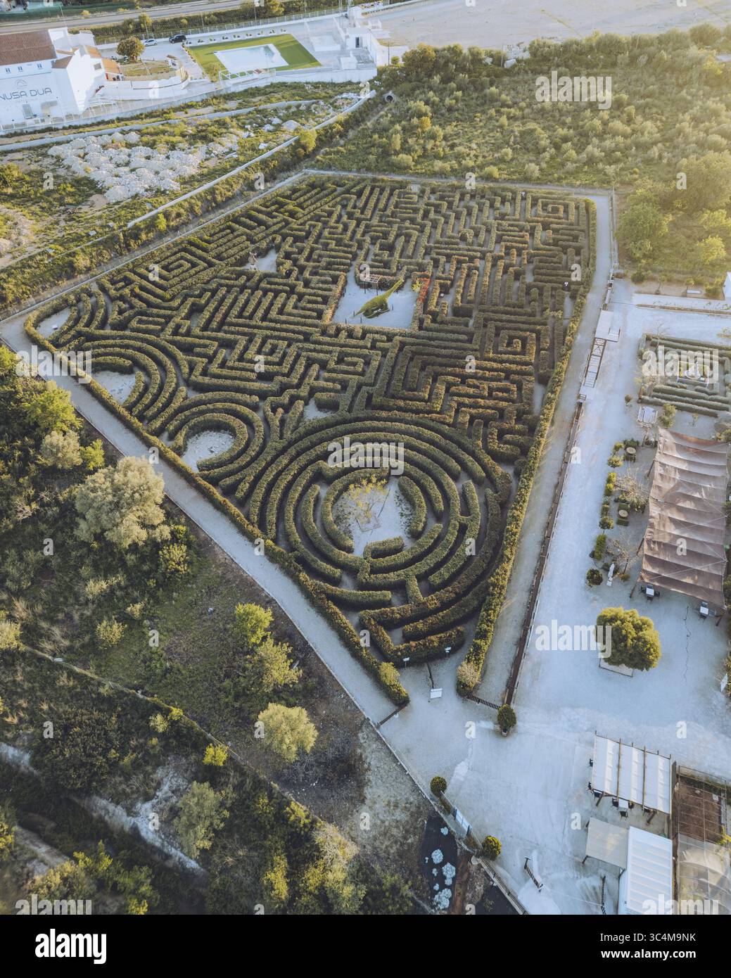 Luftaufnahme eines komplexen, geometrischen Labyrinths aus sorgfältig getrimmten Hecken, die Schatten im goldenen Licht der Abenddämmerung werfen, Peñíscola, Comunidad Valenciana, Spanien. Stockfoto