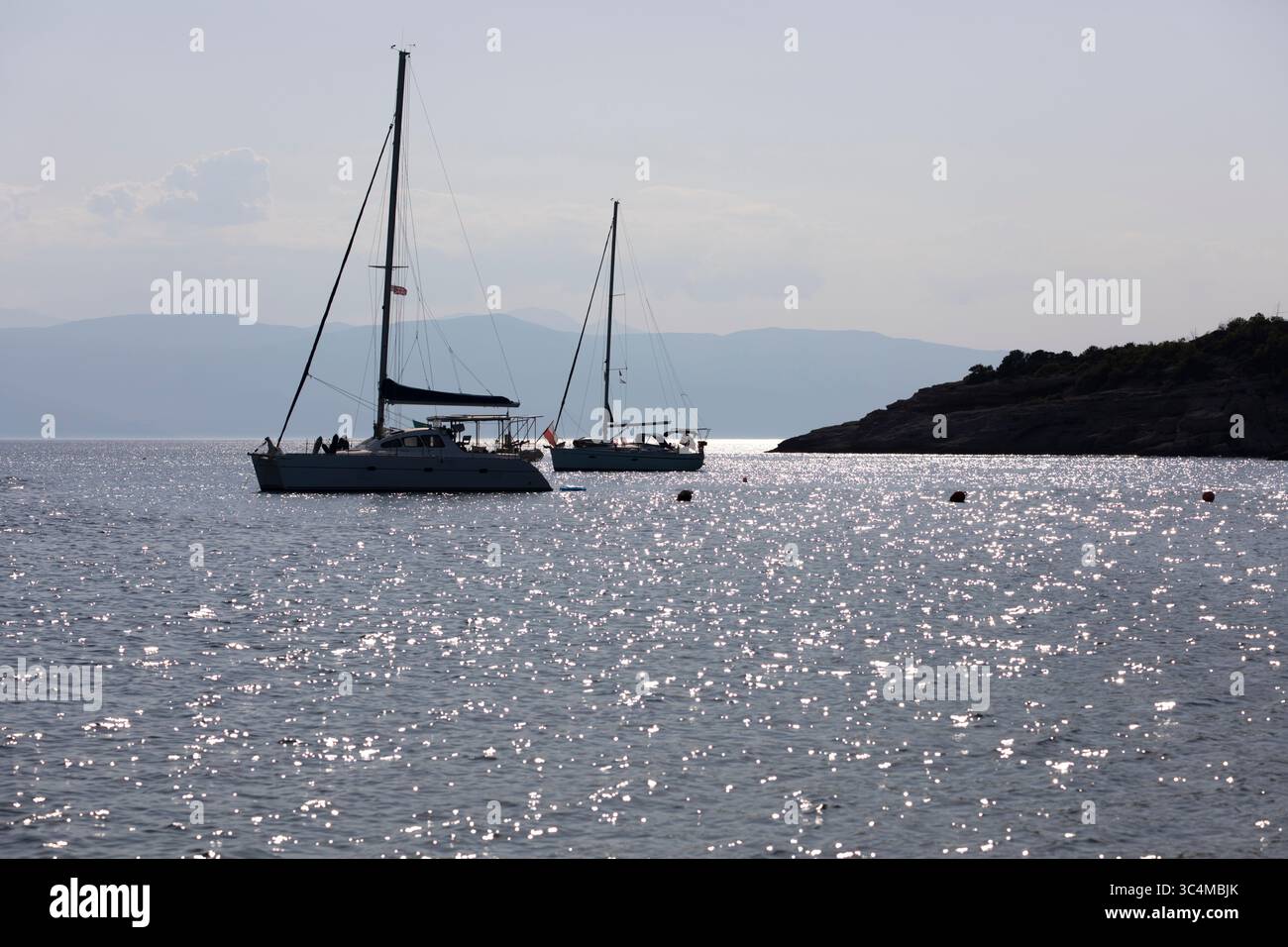 Silhouettenyachten vor der Bucht mit strahlendem Sonnenlicht auf dem Wasser, Spetses, Saronische Inseln, griechische Inseln, Griechenland, Europa Stockfoto