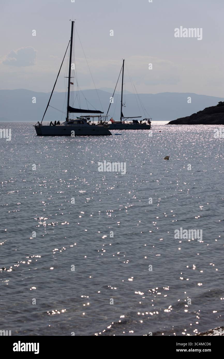 Silhouettenyachten vor der Bucht mit strahlendem Sonnenlicht auf dem Wasser, Spetses, Saronische Inseln, griechische Inseln, Griechenland, Europa Stockfoto